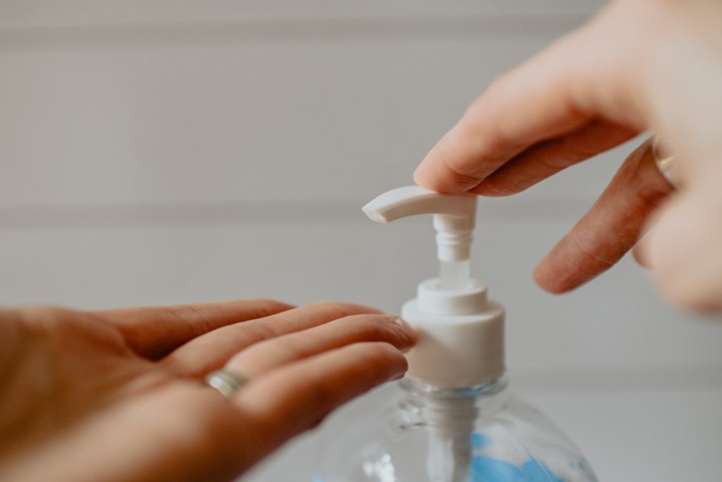 Close-up of a person dispensing hand sanitizer onto their palm from a pump bottle.
